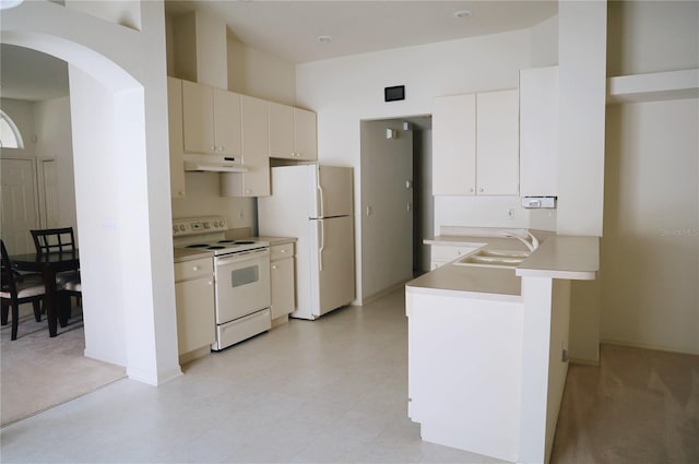 kitchen with sink, white appliances, light tile flooring, white cabinetry, and kitchen peninsula