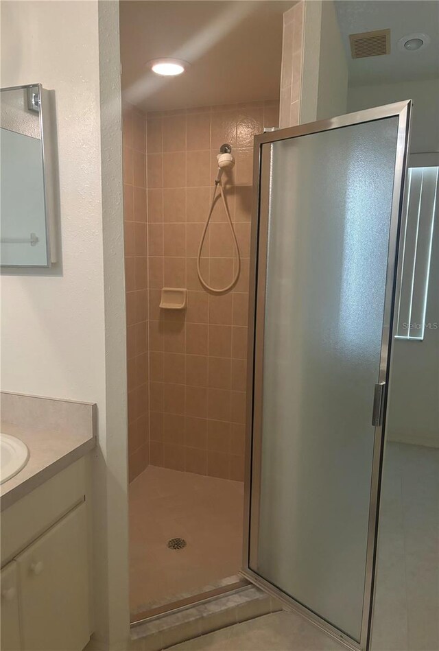 bathroom featuring tile flooring, vanity, and a shower with door