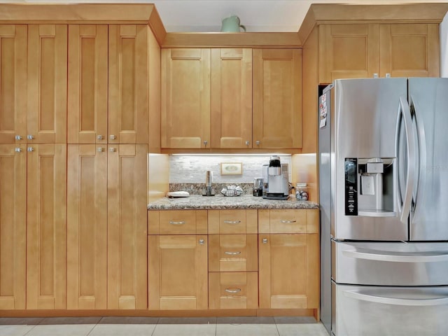 kitchen featuring stainless steel refrigerator with ice dispenser, light stone counters, and tasteful backsplash