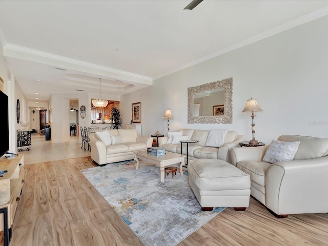 living room with ornamental molding, light tile flooring, and ceiling fan with notable chandelier