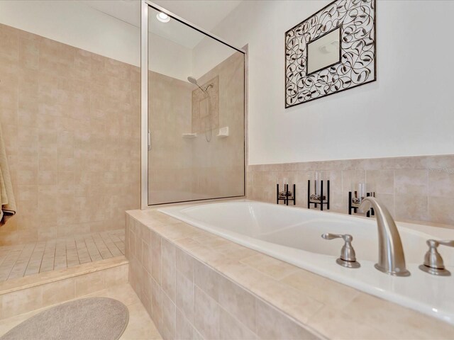 bathroom with shower with separate bathtub and tile floors