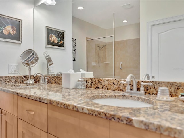 bathroom with double vanity and a shower with shower door