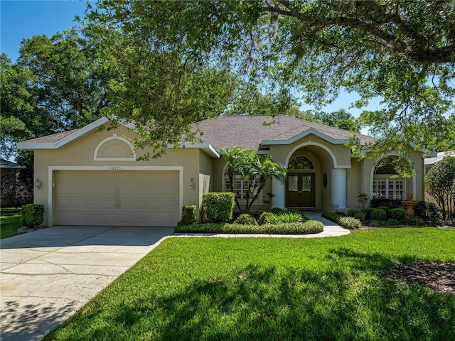 view of front facade featuring a garage, driveway, a shingled roof, stucco siding, and a front yard