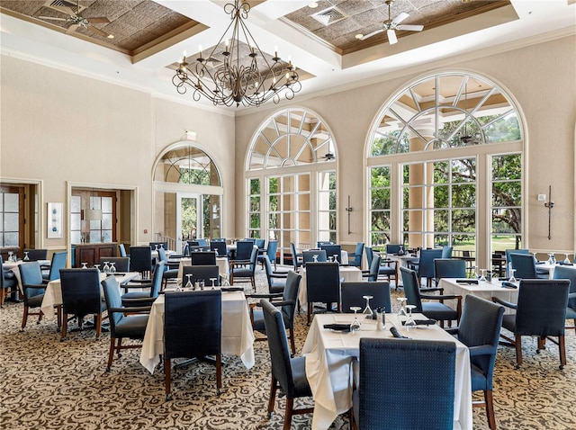 carpeted dining area with coffered ceiling, ceiling fan with notable chandelier, a high ceiling, and ornamental molding