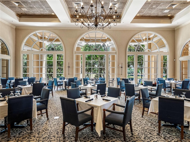 carpeted dining area with coffered ceiling, a raised ceiling, and an inviting chandelier