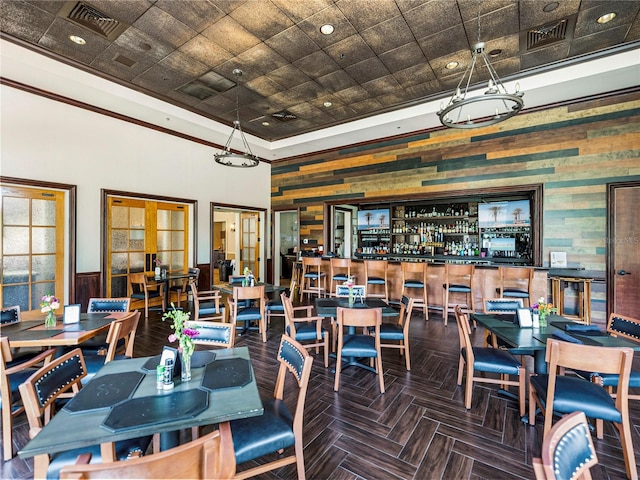 dining space with a towering ceiling, bar area, dark parquet floors, and french doors