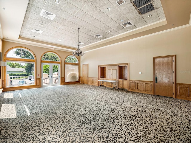 interior space featuring a wainscoted wall, visible vents, french doors, carpet, and a raised ceiling