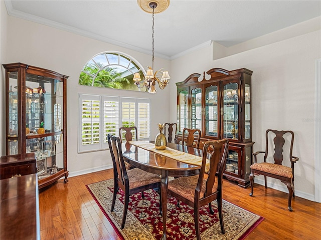 dining room with an inviting chandelier, wood-type flooring, baseboards, and crown molding