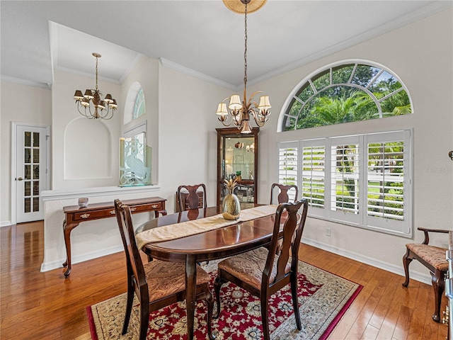 dining room featuring hardwood / wood-style floors, crown molding, baseboards, and a notable chandelier