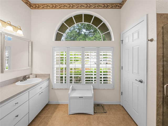 full bathroom featuring tile patterned flooring, baseboards, a tile shower, and vanity