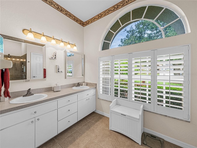 full bathroom with tile patterned flooring, a sink, baseboards, and double vanity