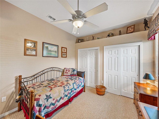 bedroom with light carpet, ceiling fan, visible vents, and two closets