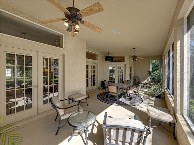 sunroom / solarium featuring a healthy amount of sunlight, visible vents, a ceiling fan, and french doors