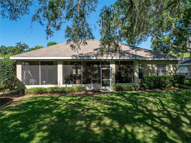 rear view of property with a sunroom, a shingled roof, a lawn, and stucco siding