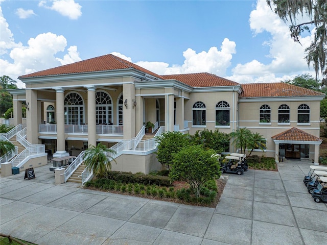 mediterranean / spanish house featuring a tiled roof, stairway, and stucco siding