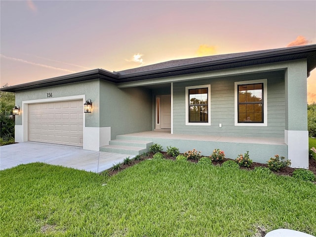 ranch-style house featuring a garage, a lawn, and covered porch