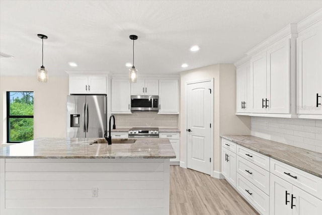 kitchen featuring stainless steel appliances, white cabinetry, hanging light fixtures, and sink