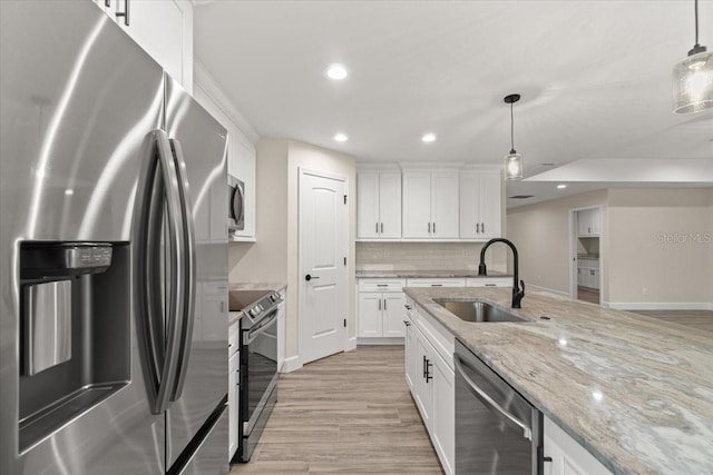 kitchen featuring appliances with stainless steel finishes, white cabinets, hanging light fixtures, and sink