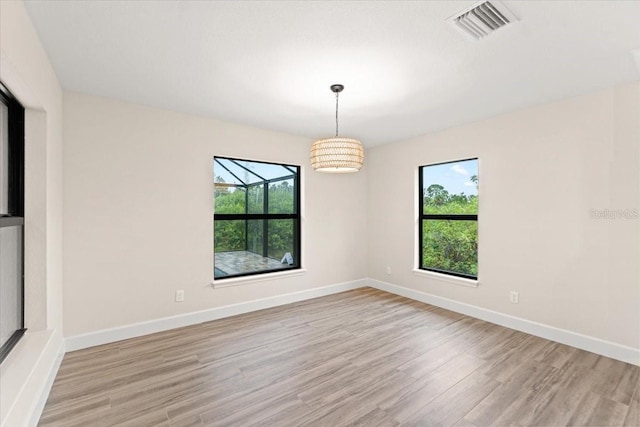 spare room featuring a notable chandelier and light wood-type flooring