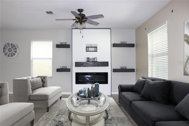 living area with a ceiling fan, a healthy amount of sunlight, a fireplace, and visible vents