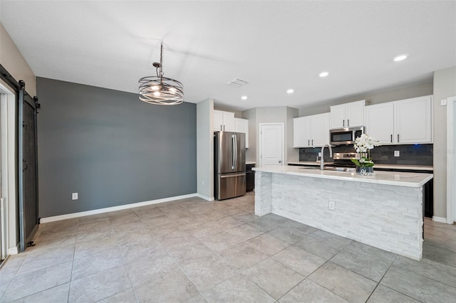 kitchen featuring light countertops, appliances with stainless steel finishes, a barn door, and white cabinets