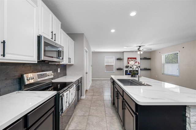 kitchen featuring a center island with sink, stainless steel appliances, backsplash, white cabinets, and a sink