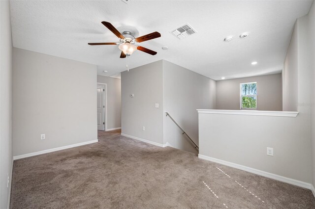 empty room with baseboards, visible vents, a ceiling fan, a textured ceiling, and carpet floors