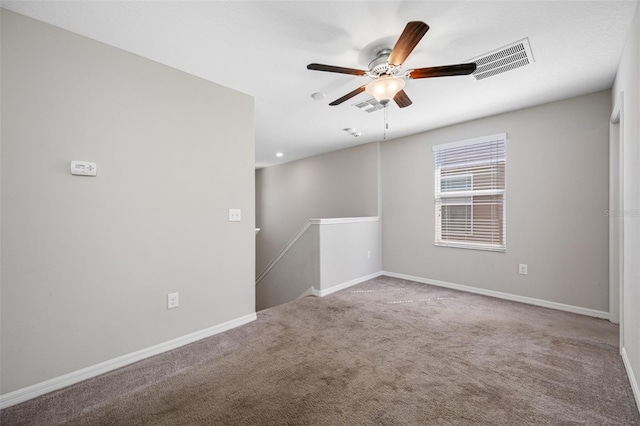 carpeted empty room with baseboards, visible vents, and ceiling fan