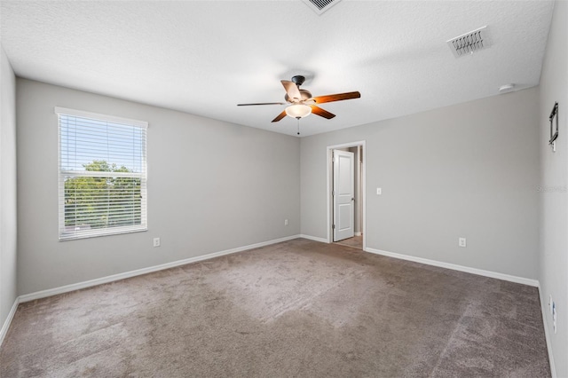 spare room featuring carpet floors, visible vents, ceiling fan, a textured ceiling, and baseboards