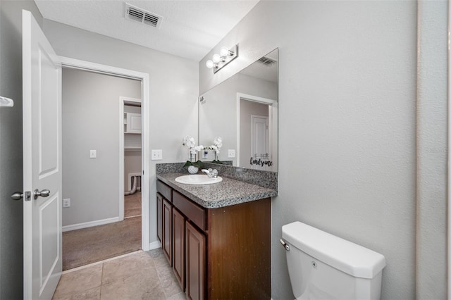 bathroom featuring toilet, vanity, visible vents, and baseboards