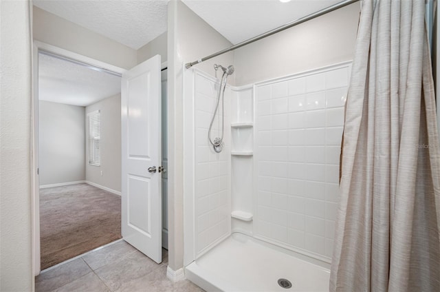 bathroom with a shower stall, a textured ceiling, and tile patterned floors