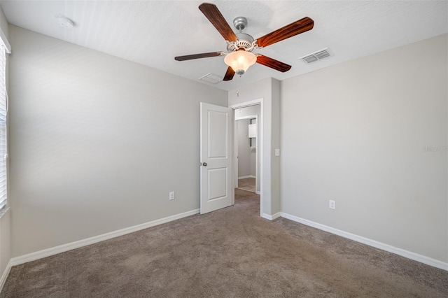 carpeted spare room featuring baseboards, visible vents, and a ceiling fan