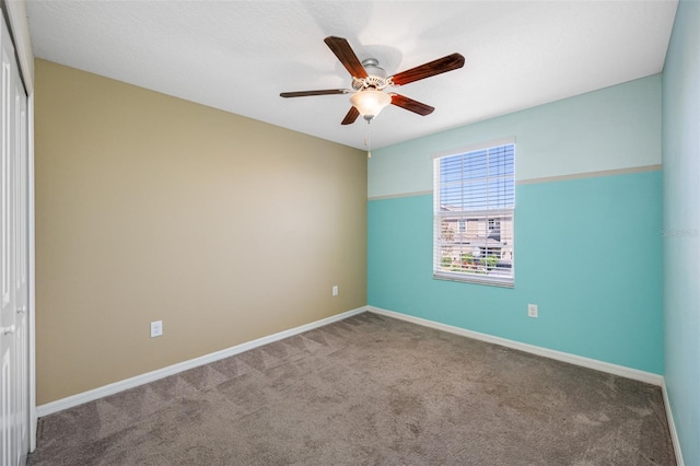 empty room with carpet flooring, a ceiling fan, and baseboards