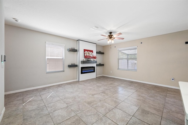 unfurnished living room with a ceiling fan, a glass covered fireplace, and baseboards