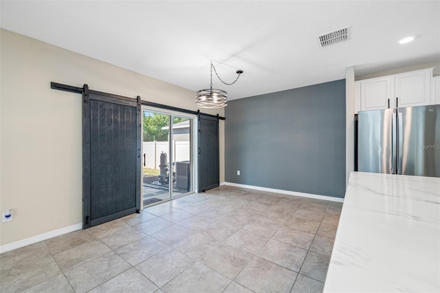 spare room featuring visible vents, baseboards, and a barn door