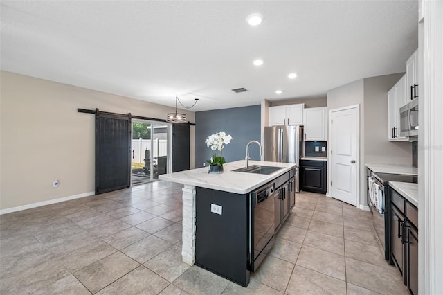 kitchen with a barn door, a sink, visible vents, light countertops, and appliances with stainless steel finishes