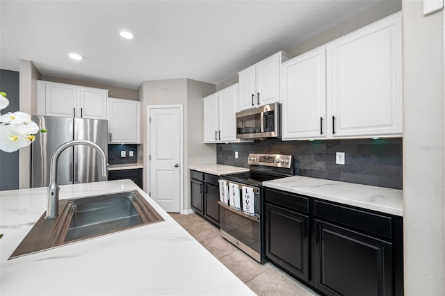 kitchen with dark cabinetry, appliances with stainless steel finishes, white cabinets, and a sink