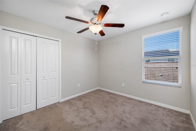 unfurnished bedroom featuring carpet, a closet, ceiling fan, and baseboards