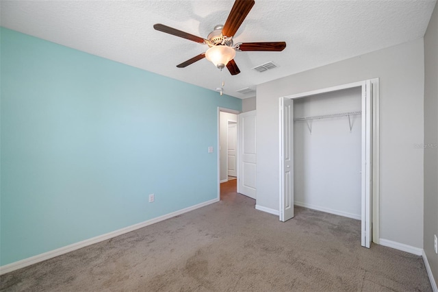 unfurnished bedroom with baseboards, visible vents, carpet, a textured ceiling, and a closet