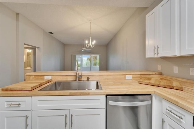 kitchen featuring stainless steel dishwasher, white cabinets, sink, pendant lighting, and wood counters