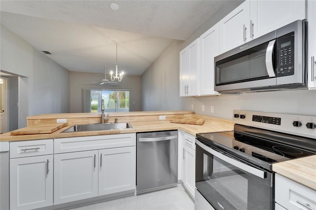 kitchen featuring kitchen peninsula, hanging light fixtures, appliances with stainless steel finishes, sink, and white cabinetry