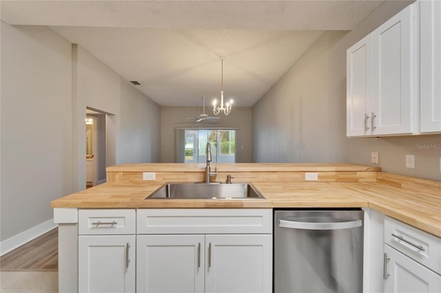 kitchen featuring wooden counters, stainless steel dishwasher, sink, white cabinets, and pendant lighting