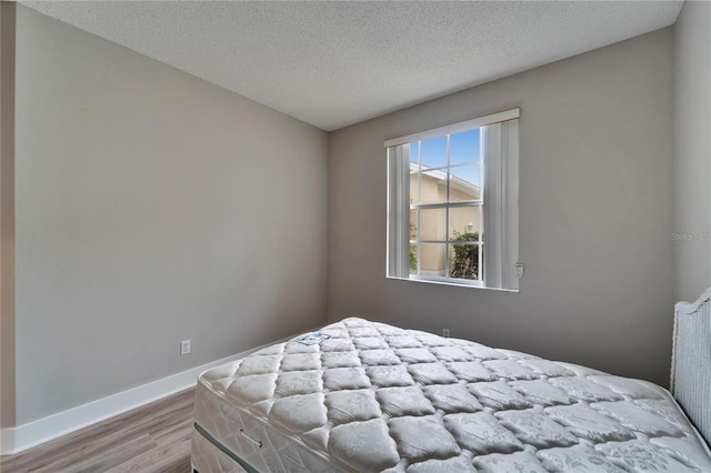 bedroom with light wood-type flooring and a textured ceiling