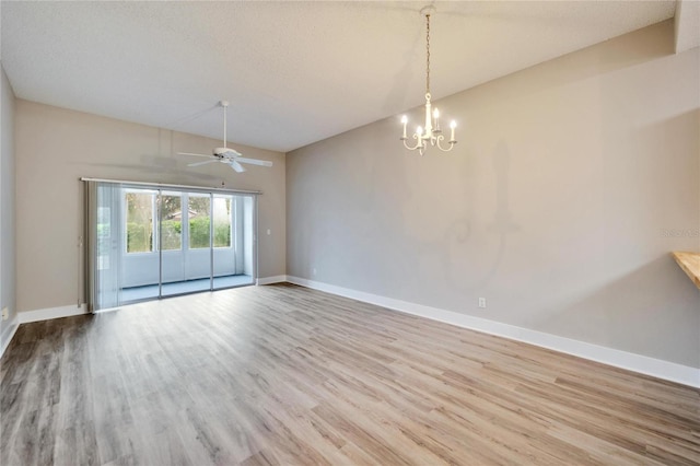 spare room with ceiling fan with notable chandelier, a textured ceiling, and light hardwood / wood-style flooring