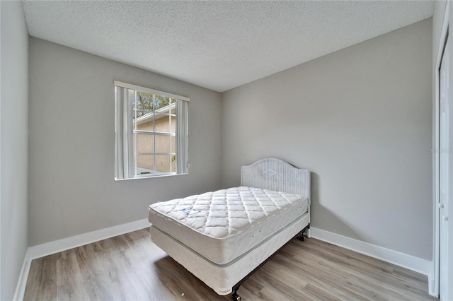 bedroom with a textured ceiling and light hardwood / wood-style flooring