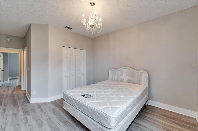 bedroom with wood-type flooring, a textured ceiling, a closet, and a chandelier