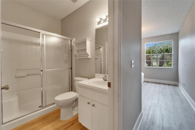 bathroom with wood-type flooring, toilet, a textured ceiling, walk in shower, and vanity