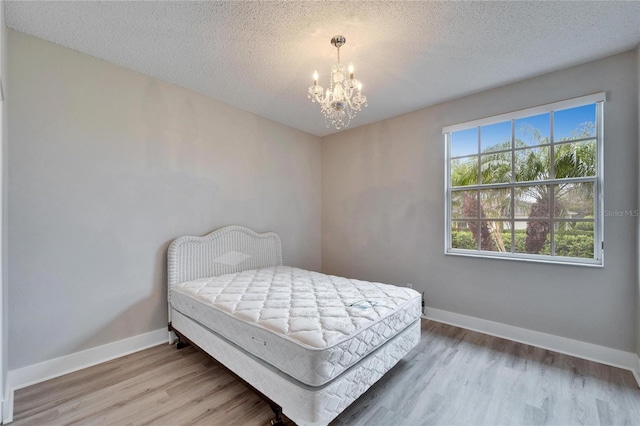 bedroom featuring multiple windows, a textured ceiling, and a notable chandelier