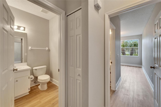 bathroom with vanity, hardwood / wood-style flooring, a textured ceiling, and toilet