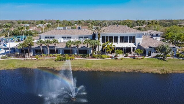 rear view of property with a water view and a lawn